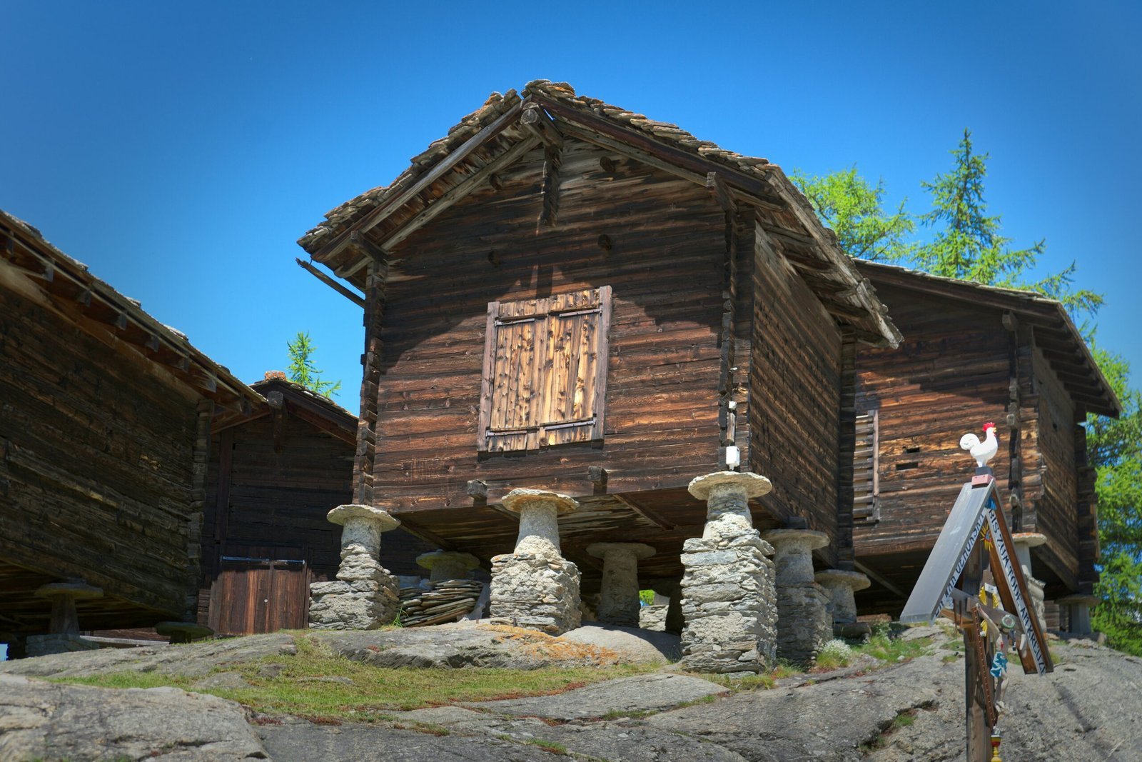 A log cabin with stone pillars and a flag pole